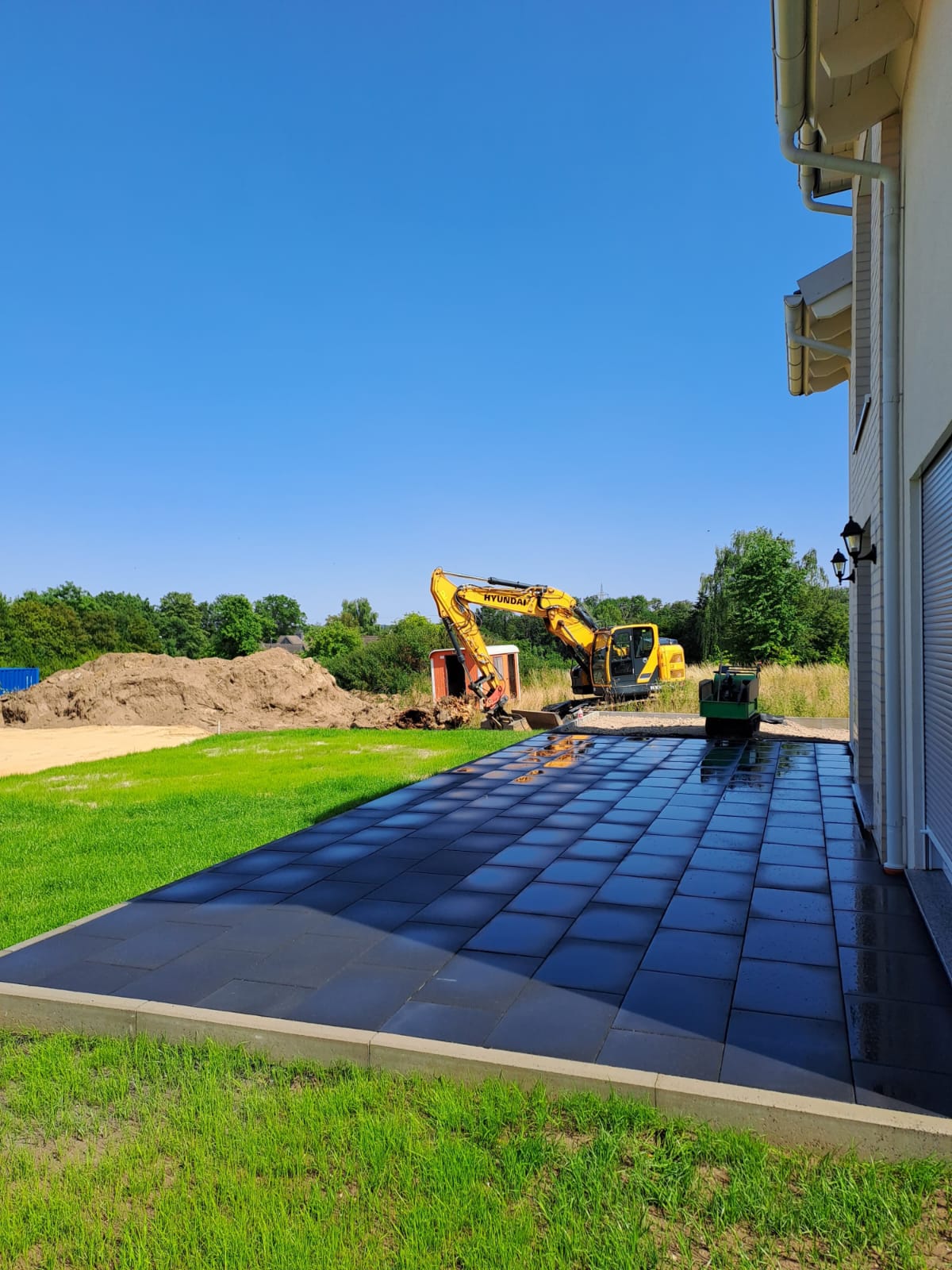 Alee din pavaj gri în lucru, cu utilaj de construcție