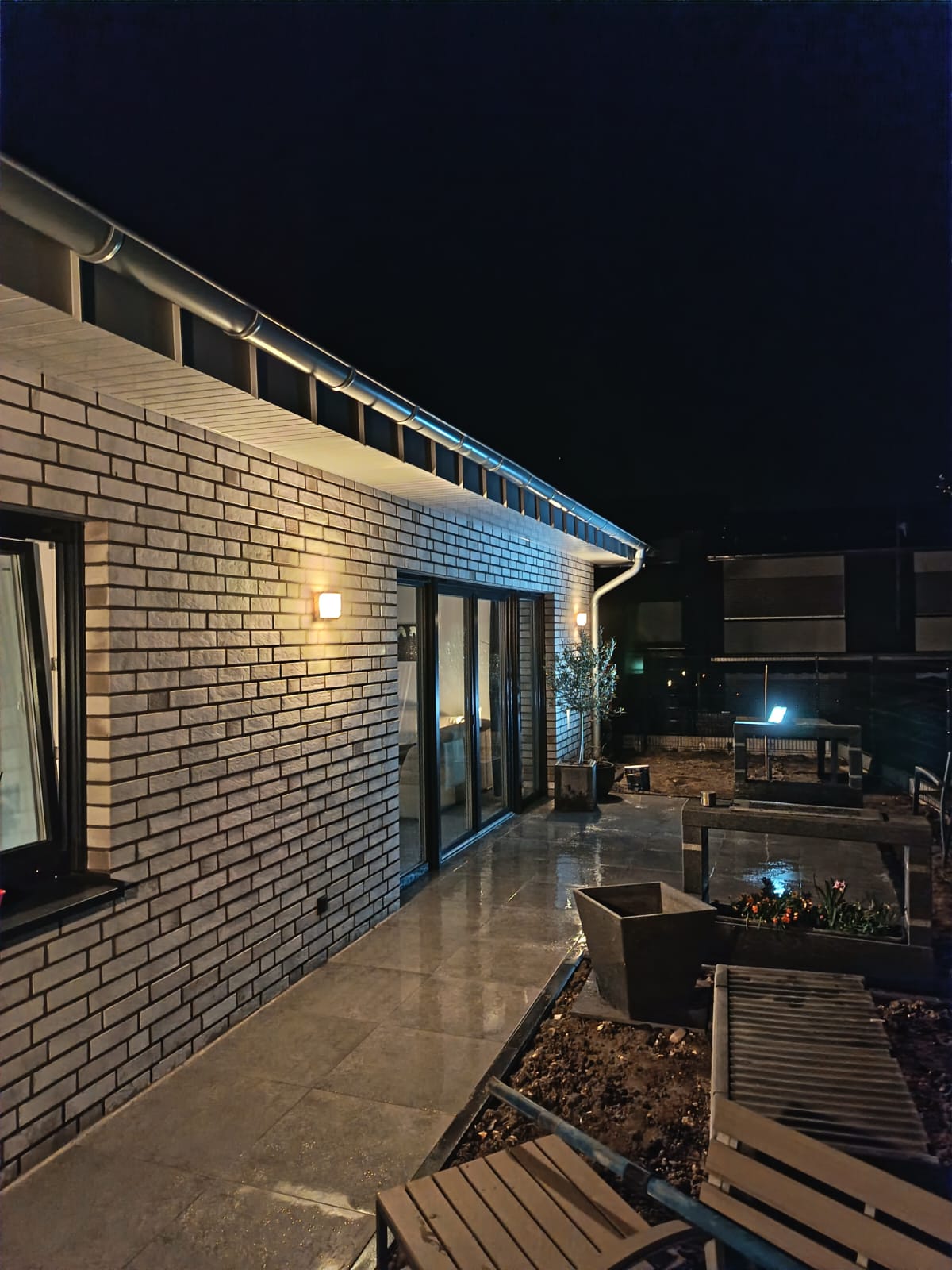 Casă din cărămidă cu terasă și iluminat exterior nocturn